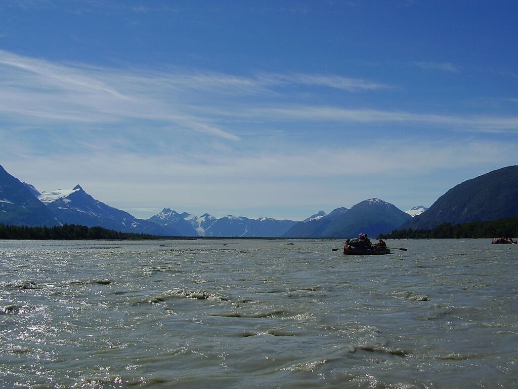 Photo showing a raft on the Tatshenshini River with mountains in the background