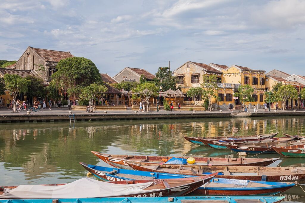 Photo showing View of Riverfront of Hội An with colourful wooden boats in the forefront.