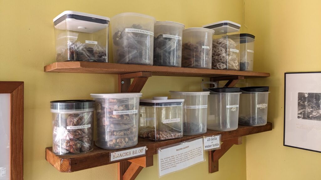 Plastic snack containers organized on a shelf clearly labeled with the name of their contents.