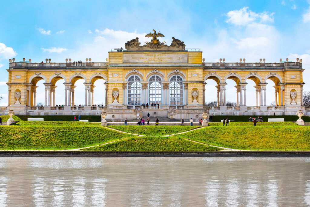 Front view of Gloriette in the Schonbrunn Garden against a blue sky with some clouds, showcasing it as the romantic palace it is