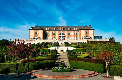 Photo showing the building of Domaine Carneros Winery with manicured gardens in the foreground.
